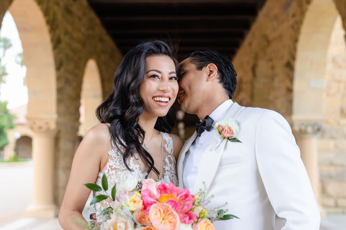 Smiling couple with pastel bridal bouquet under arches