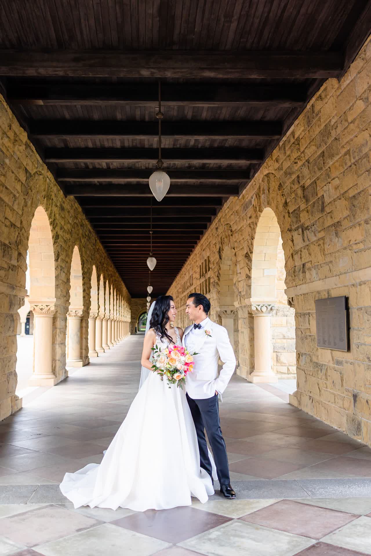 Bride and groom standing together under a floral wedding arch
